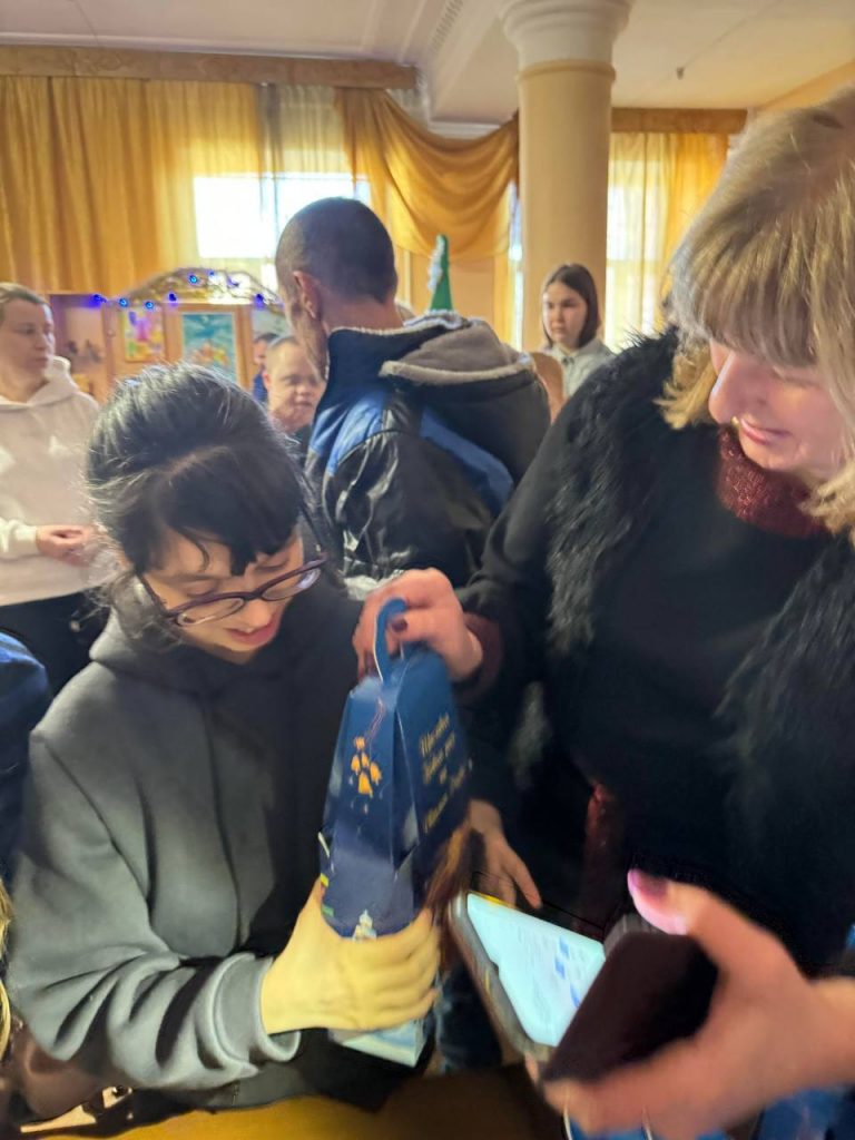 Disabled Ukrainian child receiving a chocolate gift set at a concert organised by charities Sunflower Scotland (UK) and Shira Sprava (Ukraine) in Kryvyi Rih