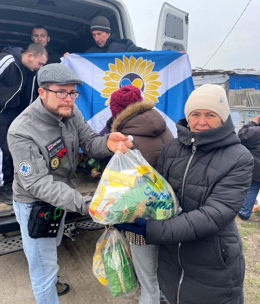 Female resident of the Osokorivka village receiving humanitarian aid from Oleg Dmitriev, charities Sunflower Scotland and Shira Sprava delivering humanitarian aid