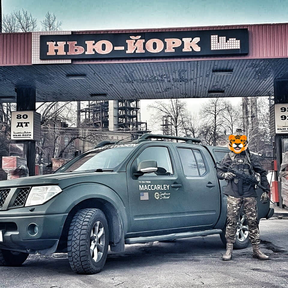 Ukraine ZSU soldier stands near 4x4 truck Nissan Navara delivered by Sunflower Scotland to Donbas