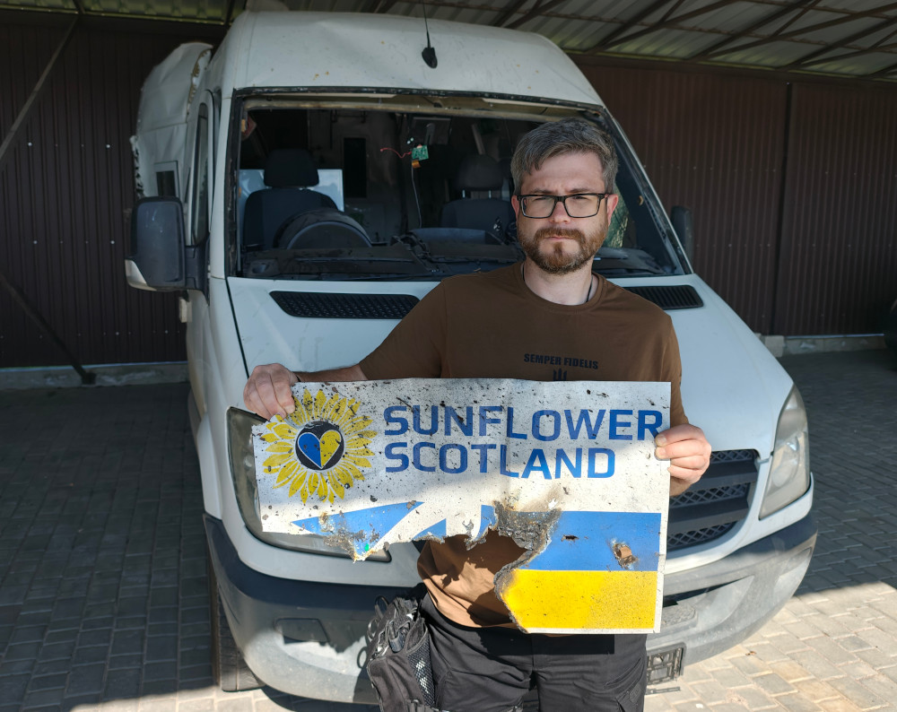 Oleg Dmitriev in front of Sunflower Scotland's armoured van destroyed by Russian FPV drone